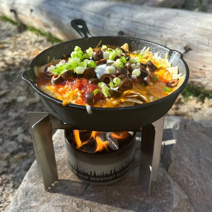 A skillet of food cooking on the camp stove over a City Bonfire